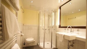 A modern bathroom with a glass-enclosed shower, a white toilet, and a sink with a mirror above it. - Wald-cafe Landhotel Restaurant (Bonn)