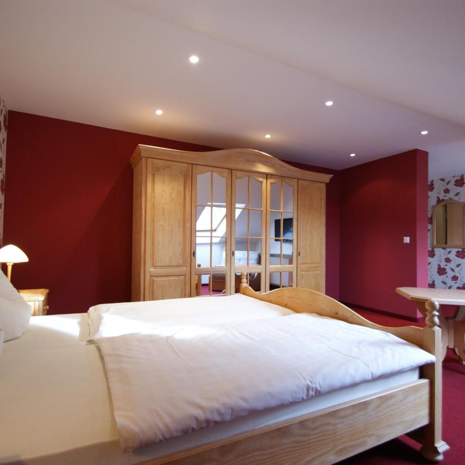 Een slaapkamer met een bed, een houten garderobe en een bureau.