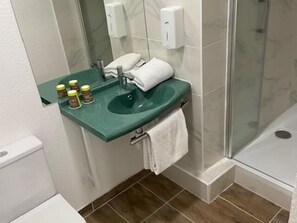 A bathroom with a green countertop sink, a mirror, a towel rack, and a glass shower enclosure. - Hotel Classeco Gent (Ghent)