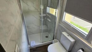 A bathroom with a glass-enclosed shower, a toilet, and a window. - Hotel Classeco Gent (Ghent)