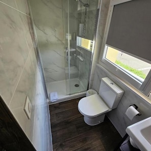 A bathroom with a glass-enclosed shower, a toilet, and a window. - Hotel Classeco Gent (Ghent)