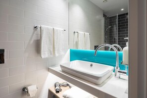 Une salle de bain moderne avec des murs recouverts de carreaux blancs, un lavabo blanc et un mur d’accent bleu.
