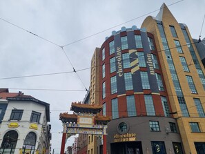 A building with a chocolate-themed facade, a traditional Chinese gate, and a sign for 'Panos.' - Holiday Inn Express Antwerp - City Centre, an IHG Hotel (Antwerp)