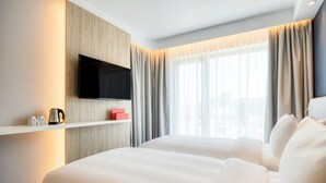 A hotel room with a large bed, a flat-screen TV mounted on a wooden panel, a coffee maker, and a red box on a shelf. - Holiday Inn Express Antwerp - City Centre, an IHG Hotel (Antwerp)