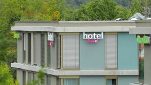 Ein modernes Hotel mit flachem Dach, vielen Fenstern und einem Schild, das es als Hotel kennzeichnet.