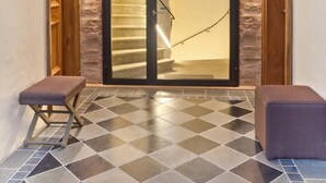 A hotel entrance with a checkered floor, a staircase, and a wooden bench. - Hotel David (Regensburg)