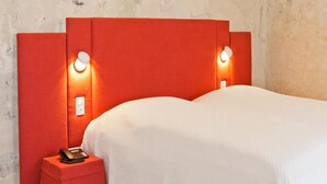 A hotel room with a red headboard, bedside lamps, a telephone, and a white bedspread. - Hotel David (Regensburg)