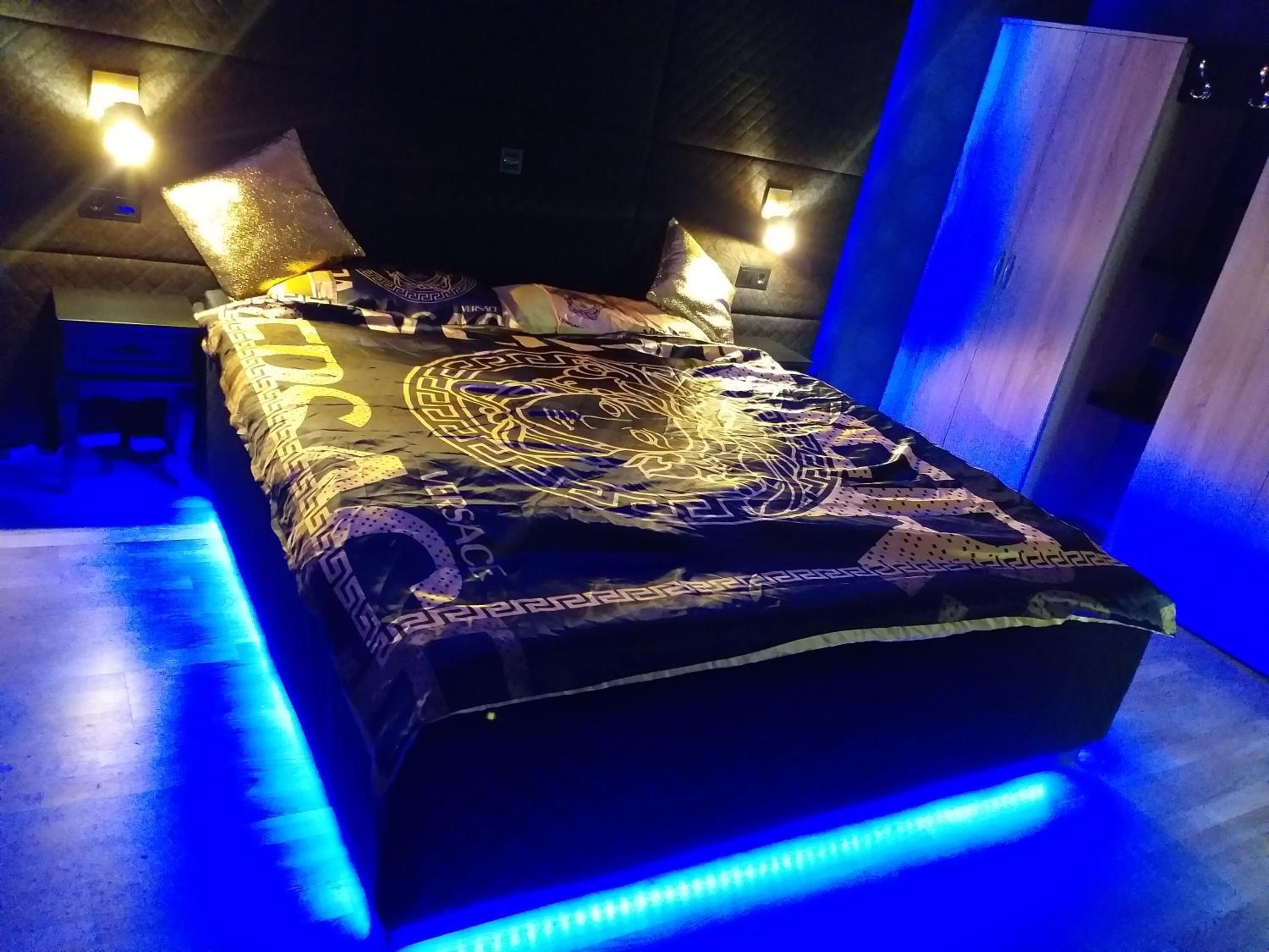 Ein Bett mit gemustertem Bettbezug und Kissen, ein Nachttisch und Wandleuchten.