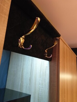 Ein Eckbereich eines Raumes mit einem Holzschrank und einer Wand mit schwarzer Struktur.