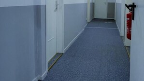 A corridor with white and grey walls, doors, and a blue carpet. - Hotel Tyros am Weidendamm (Hannover)