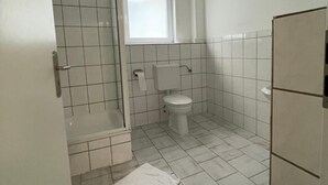 A small, clean bathroom with a toilet, a shower, and a window. - Hotel Tyros am Weidendamm (Hannover)