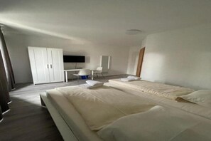 A modern hotel room with a large bed, a desk, and a chair. - Hotel Tyros am Weidendamm (Hannover)