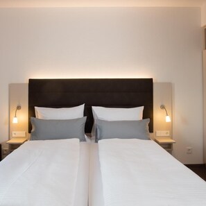 A double bed with a dark headboard, two bedside tables with lamps, and a plain wall.