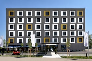 Un edificio moderno con una griglia di finestre e un ingresso centrale.