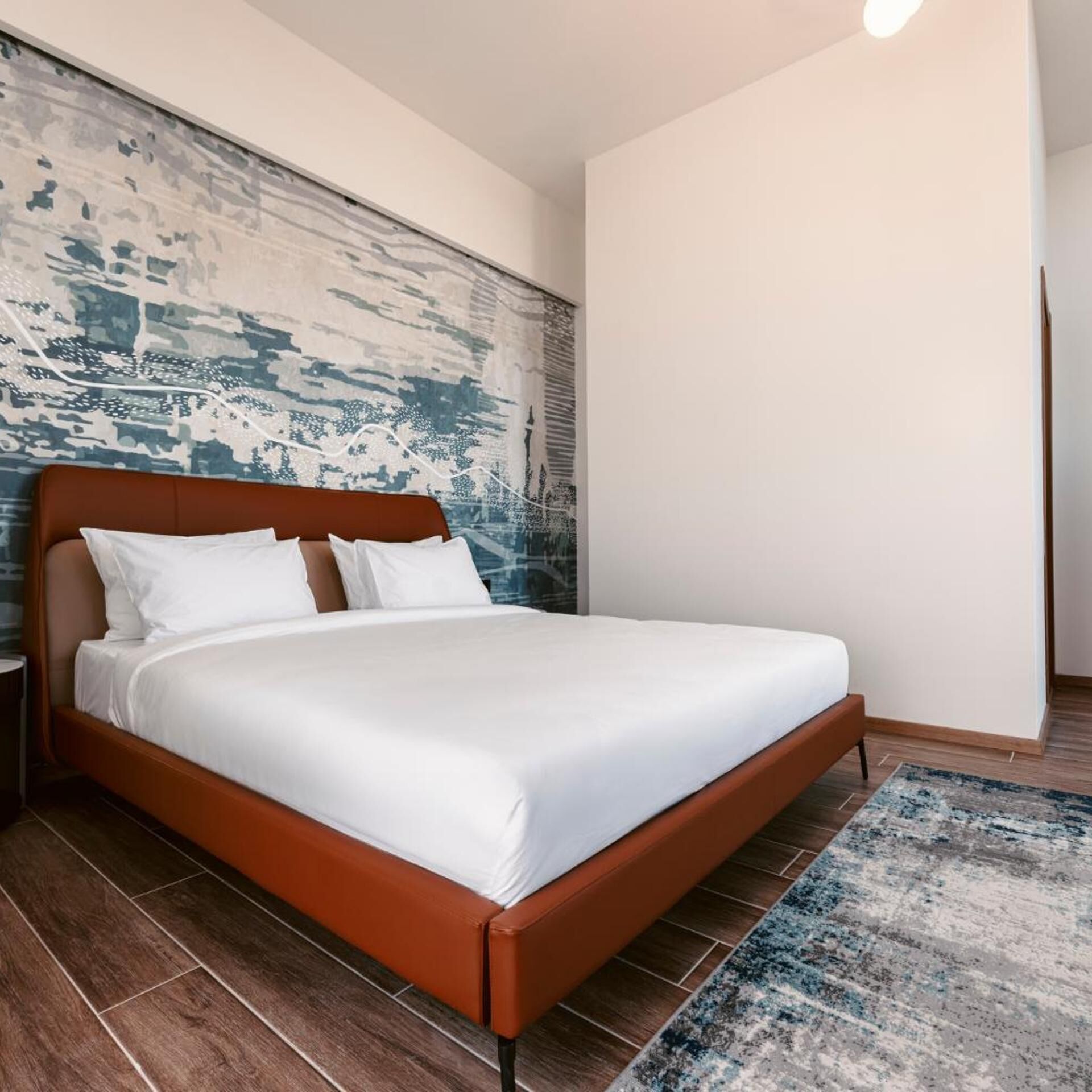 Una camera da letto moderna con un letto in legno, biancheria da letto bianca e un tappeto decorato.