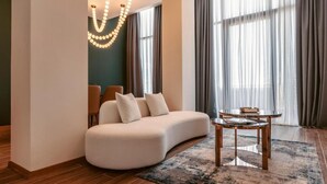A modern living room with a curved sofa, a round coffee table, and a chandelier. - Kass Diamond Resort (Tsalka)