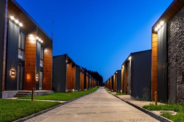 A row of modern buildings with a central pathway, likely part of a hotel or resort.