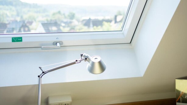 Une fenêtre de toit, une lampe de bureau, un bouton-poussoir et une vue sur un paysage.