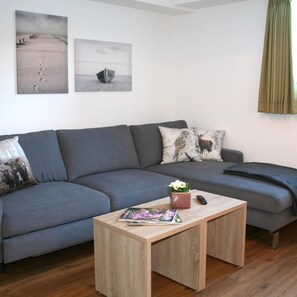 A modern living room with a grey sofa, a wooden coffee table, and two wall-mounted pictures. - Lahn Hotel (Biedenkopf)