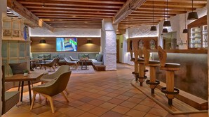 Eine geräumige Lobby mit hoher Decke, Holzbalken und einer zentralen Sitzecke mit Sofas und Sesseln.
