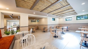 Un café espacioso con mesas y sillas de madera, un techo alto con diseño de madera natural y un interior moderno y limpio.