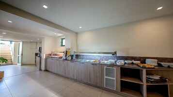 A modern kitchen with a long counter, various food items, and a ventilation system.