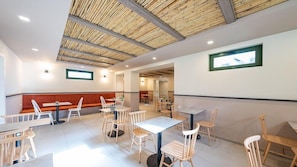 A modern restaurant interior with wooden ceiling beams, white walls, and a mix of wooden and metal furniture. - Erato Beach Hotel - Adults Only (Platanias)