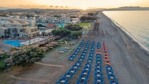 Een kusthotel met een zwembad, ligbedden en parasols.