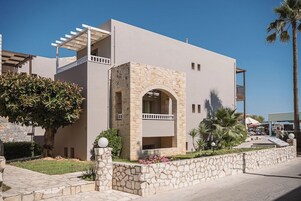 Un edificio moderno con un arco de piedra en la entrada, un balcón y un camino empedrado.