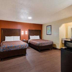 Habitación de hotel con dos camas, un escritorio y televisión.