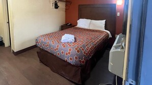 Ein Hotelzimmer mit Bett, Nachttisch, Telefon und Heizung.