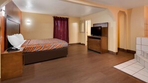 Ein Schlafzimmer mit Bett, Kommode, Fernseher und einem Badezimmer mit Fliesenboden.