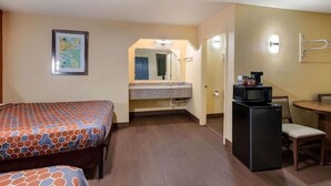 Ein Hotelzimmer mit Bett, einer kleinen Küchenzeile, einem Esstisch und einem Spiegel.