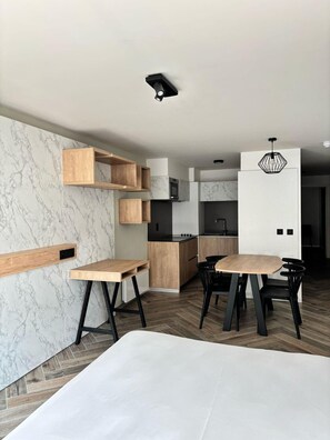 Een moderne keuken met inbouwapparatuur, houten planken en een eetgedeelte met een tafel en stoelen.