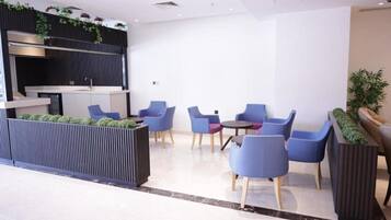 Un espace de détente moderne avec des sièges bleus, un comptoir d’accueil noir et un jardin vertical.