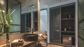A modern bathroom with a large mirror, a round sink, and a wooden vanity. - Be House Suites & Spa by Nobile (Punta del Este)