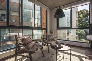 A modern room with large windows, a round table, and two chairs. - Be House Suites & Spa by Nobile (Punta del Este)