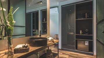 A modern bathroom with a large mirror, a round sink, and a wooden vanity.