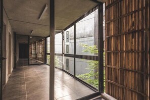 A corridor with large windows and a view of greenery outside. - Be House Suites & Spa by Nobile (Punta del Este)