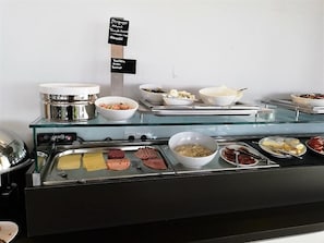 Ein Buffet mit verschiedenen Speisen und einem Schild, das Frühstücksmöglichkeiten anzeigt.