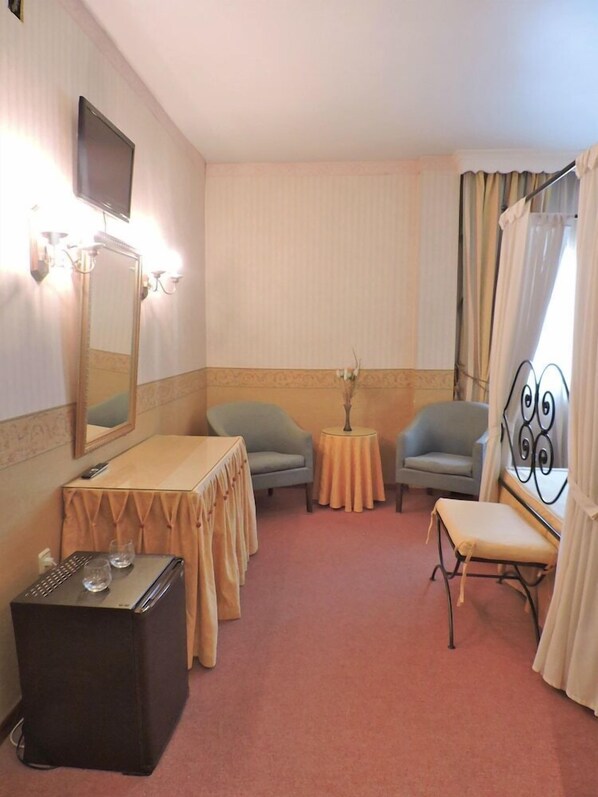 A hotel room with a bed, a desk, two chairs, a small table, a mirror, and a television. - Hotel Las Yucas (Atarfe)