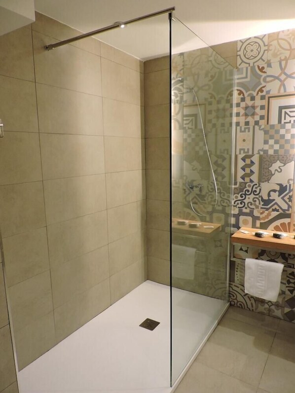 A modern bathroom with a glass-enclosed shower, tiled walls, and a patterned backsplash. - Hotel Las Yucas (Atarfe)