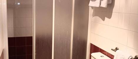 A bathroom with a shower, toilet, sink, and a checkered floor.