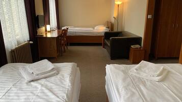 Ein Hotelzimmer mit zwei Betten, einem Schreibtisch, einem Sessel, einer Couch und einer Lampe.