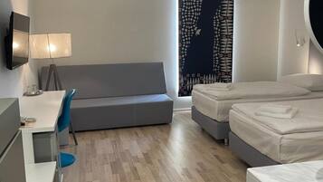 A modern hotel room with a desk, a sofa, a bed, and a patterned curtain.