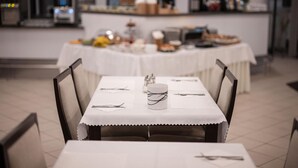 Een eetruimte met een tafel gedekt voor twee personen, stoelen en een buffettafel op de achtergrond.