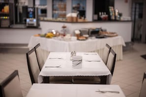 A dining area with a table set for two, chairs, and a buffet table in the background. - Hotel Metropol CB (České Budějovice)