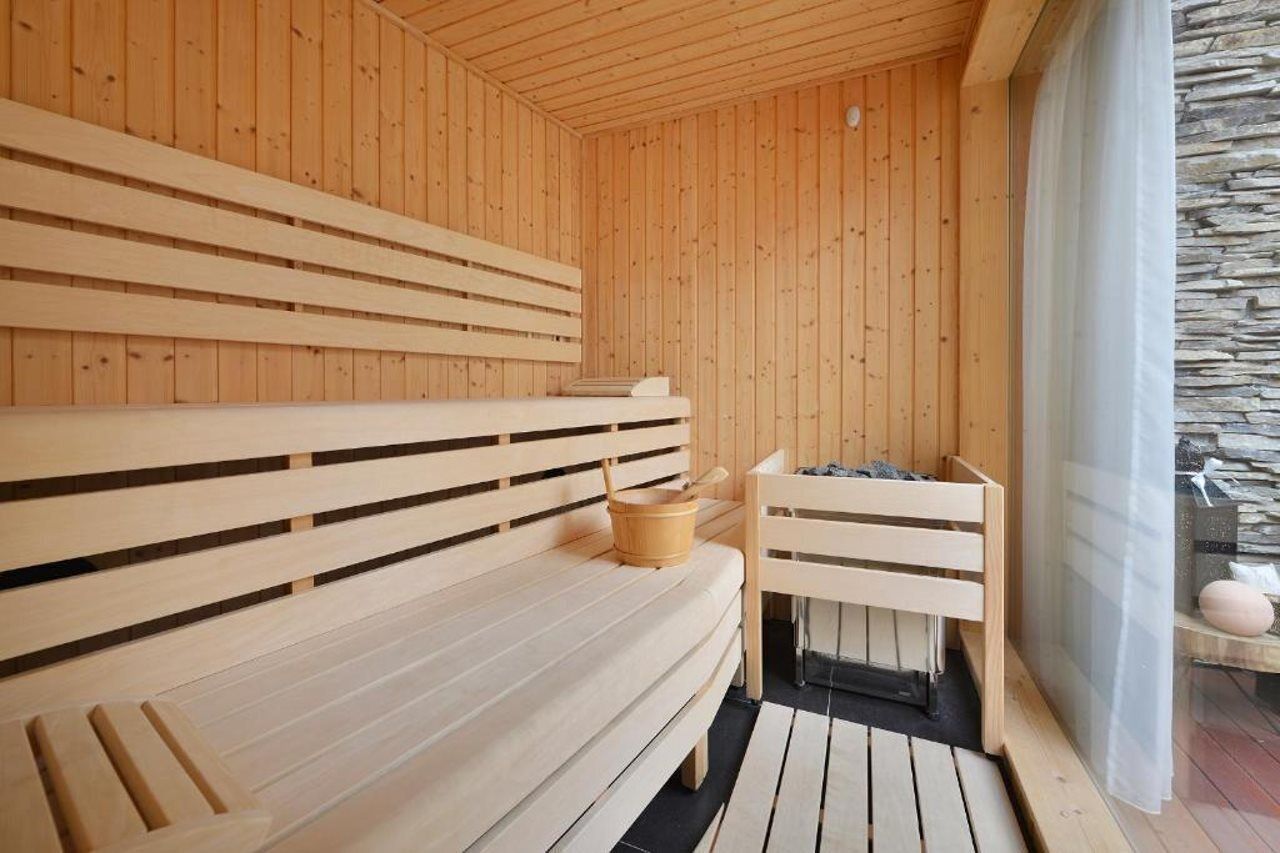 Una sauna de madera con bancos y una pared de piedra.