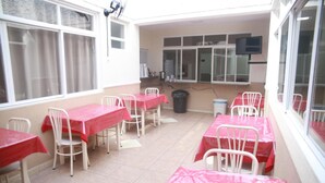 A dining area with tables and chairs, a trash bin, and a television mounted on the wall. - Hotel Jurubatuba (São Bernardo do Campo)