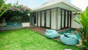 Una casa moderna con piscina, césped verde y un porche cubierto.